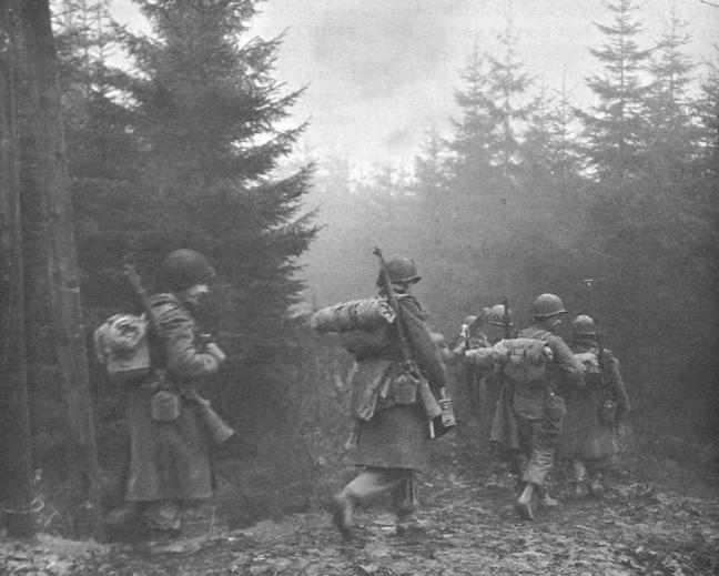 Troops of the 325th Glider Infantry moving through fog in the Ardennes during the Battle of the Bulge.