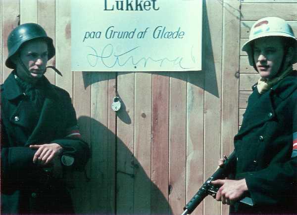 Two Danish resistance fighters guard a shop with a sign saying, ‘Closed due to Happiness’, after the liberation of Denmark by British troops