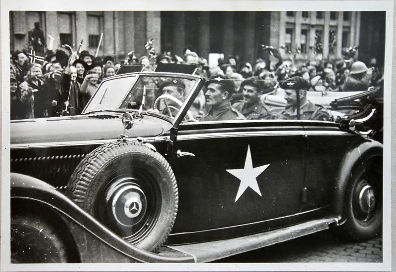 Major General Urquhart in a commandeered German staff car enjoys the warm welcome of the Norwegian crowds.